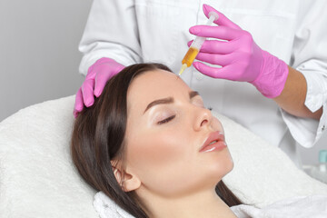 Cosmetologist does prp therapy on the face of a beautiful woman in a beauty salon. Cosmetology concept.