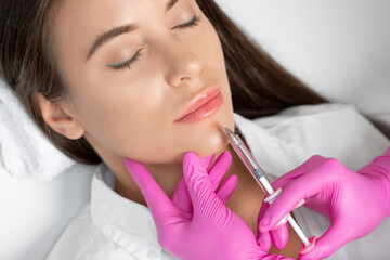 Cosmetologist does injections for lips augmentation and anti wrinkle in the nasolabial folds of a...