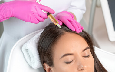 Cosmetologist does prp therapy against hair loss and anti-dandruff of a beautiful woman in a beauty...