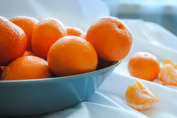 Ripe juicy tangerines in a deep ceramic plate.