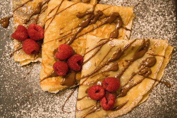 Crepes filled with chocolate with raspberries and glazed sugar