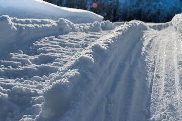 Fototapeta na wymiar Snowmobile tracks in deep snow. Twisting traces of a snowmobile crossing snow covered field