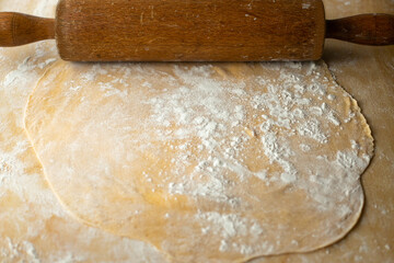 Rolled out pasta dough and a wooden rolling pin.