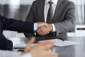 Unknown business people are shaking hands after contract signing in modern office, close-up. Handshake as successful negotiation ending