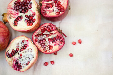 several open red pomegranate fruits with grains on a white cloth.