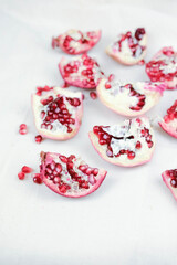 several open red pomegranate fruits with grains on a white cloth.