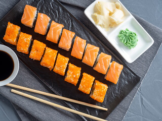 roll Philadelphia and California on a black plate. Top view, flat lay. ginger, wasabi and soy sauce nearby. traditional Japanese cuisine