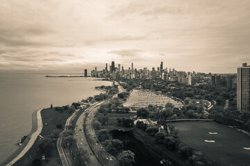 Beautiful black and white aerial skyline view of the City of Chicago along Lincoln Park with Lake Michigan, traffic on Lake Shore drive, construction, and driving range below and cloudy sky above.