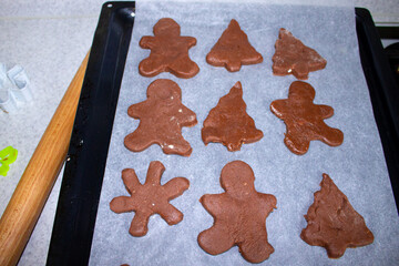 Fototapeta na wymiar Baking chocolate chip cookies. Christmas pastries. View from above. Cookies in the form of a Christmas tree, a man, and a snowflake. Homemade baked goods. Cones, oranges, red berries, and a candle 
