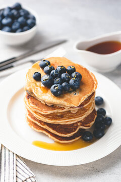 Homemade pancakes with blueberries and maple syrup on white plate. Sweet breakfast food. Toned image