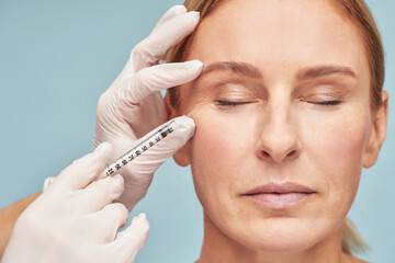 Anti aging treatments. Beautiful mature woman keeping eyes closed while receiving hyaluronic acid...