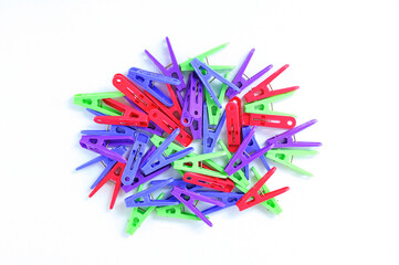 Multi-colored clothespins heap on  white background.