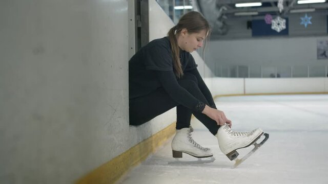 Young woman tying shoelaces on her skates