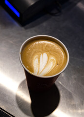 A coffee - cappuccino on a take away paper cup, top view.