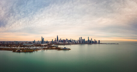 Naklejka premium Wide angle Chicago city skyline aerial panorama with Northerly Island and Lake Michigan in foreground and highrise skyscraper buildings along the horizon with a beautiful orange and blue sunset sky.