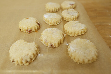 woman prepares butter cookies at home in the kitchen, the table is sprinkled with flour, rolls out the dough, cuts out the shape, the concept of cooking festive food, christmas sweets
