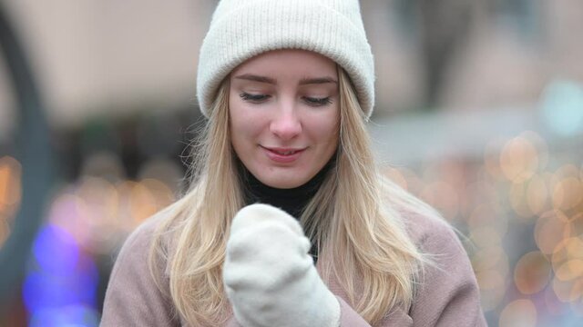 Portrait of a young girl in a polto hat and mittens against the background of festive lights at the Christmas city fair. Happy New Year