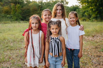 A group of cheerful girls are smiling and playing in the Park during sunset. Children's summer camp