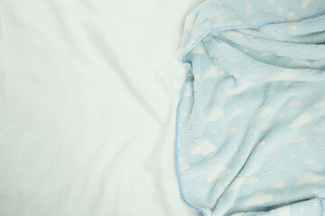 soft, pleasant to the body blue blanket on a white sheet, top view