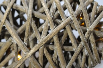 Close-up (macro shoot) of three-dimensional weaving of wicker with lights as a natural gray-brown background or texture