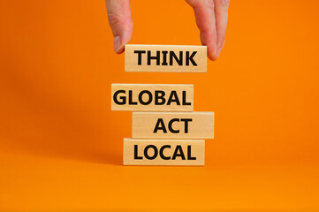 Think global act local symbol. Wooden blocks form the words 'Think global act local' on beautiful orange background. Male hand. Beautiful background. Business and think global act local concept.