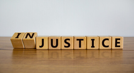 Justice instead of injustice. Turned cubes and changed the word 'injustice' to 'justice'. Beautiful wooden table, white background, copy space. Business and justice or injustice concept. - obrazy, fototapety, plakaty