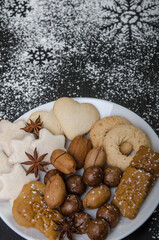 White bowl with gingerbread, nuts and spices on a black background.