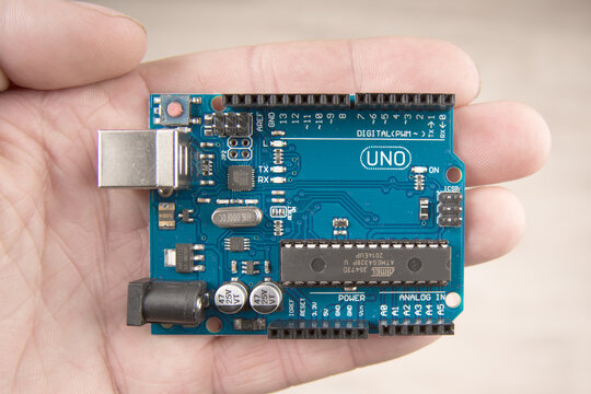 Arduino Uno board electronics in hand for programming the microcontroller
