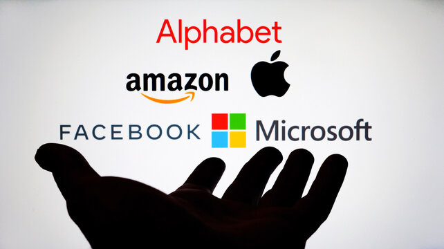 Big Five companies. Big Tech company logos: Alphabet, Amazon, Apple, Facebook, Microsoft on a screen and a silhouette of hand. Not a montage.  Digital tax, antitrust. Stone / UK - February 12 2020: 