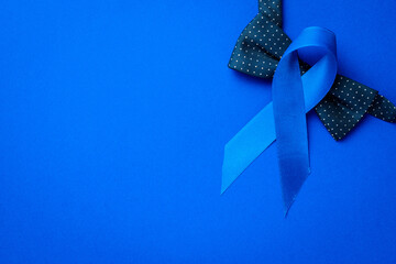 November. Blue ribbon, fashion bowtie isolated on deep blue background. Awareness prostate cancer...