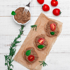 Chicken liver pate. Sandwiches, canapes with pate with cherry tomatoes on a white wooden background.