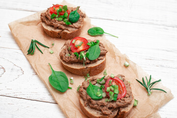Sandwiches, canapes with chicken pate, tomatoes. On a white wooden background.