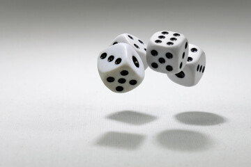  White playing dice cubes in motion on the white canvass surface