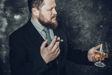Solid confident bearded man in suit with glass of whisky and cigar