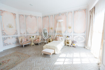 Luxurious expensive interior design of the children's room in the old Baroque style in beige colors