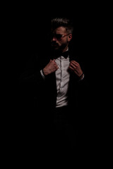 bearded young man with sunglasses adjusting black velvet tuxedo