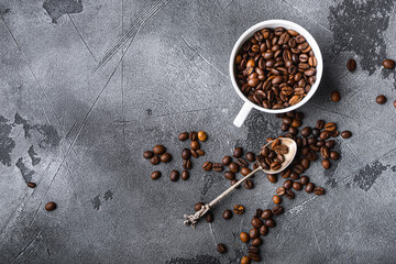 Roasted coffee beans in cup on grey textured background, top view with space for text