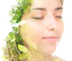 A double exposure portrait of a young beautiful brunette with her eyes closed and tree leaves...