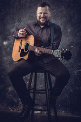 Fototapeta na wymiar Mature musician plays acoustic guitar emotional studio portrait.