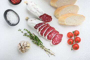 Fototapeta na wymiar Spanish salcichon slices with panini and herbs on white textured background