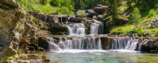 Panoramic waterfall in stands or terraces in green landscape between trees and mountains in Ordesa. Soaso stands.

