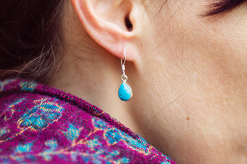 Female ear wearing elegant silver turqoise gemstone earring