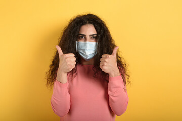 Obraz premium Girl is optimistic about the defeat of covid 19 coronavirus. yellow background.