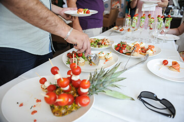 Shallow depth of field (selective focus) image with a man taking aperitifs from an open buffet table.