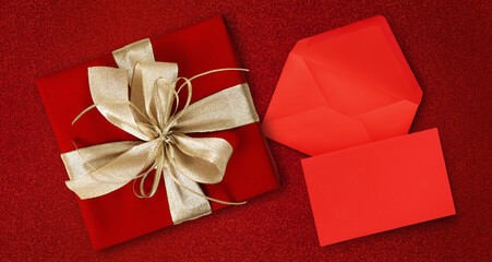 merry christmas, top view of wrapped gift present packages with golden ribbon bow, envelope and greeting card , isolated on red background, useful as gift card