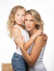Beautiful blonde mother in singlet, and similar looking curly daughter together in studio, white background.