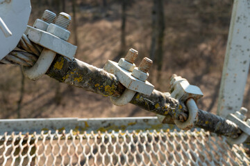 Cables and ropes of the suspension bridge close-up. Repair of the old bridge over the river. Rusty...