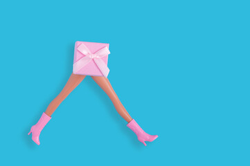 Creative Christmas and New year shopping concept with woman legs and pink gift box on pastel blue background.