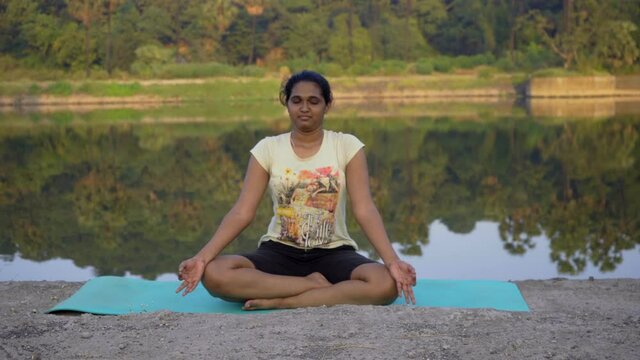 Indian girl meditating doing meditation by the lake side  Mumbai India thane