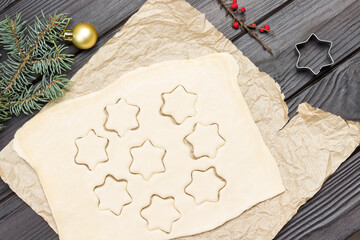 Cutting shaped cookies by mold on paper. Fir branches and mold